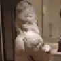 Two Wrestlers in rough light-colored clay on a dark base in a gallery setting.