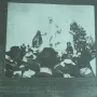 Crowd gathered around the Monument to Giuseppe Gioachino Belli, with a tall statue of a man in a top hat at the center.