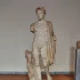Hermes Criophorus marble statue of a youthful nude figure beside a ram, with a cap and drapery over one shoulder.