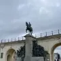 The Monument of Leopold II, a dark bronze equestrian statue on a stone pillar with sculptural figures at the base.
