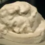 Head of Saint John the Baptist sculpture in white stone, shown resting horizontally in a bowl-like receptacle.