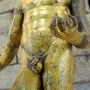 Gilded torso of Hercules of the Forum Boarium holding a club and small round objects.