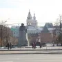 Monument to Karl Marx in a Moscow plaza, with a large stone statue on a rough base near trees and surrounding buildings.