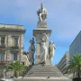 Monument to Vincenzo Bellini with a seated figure atop a tall pedestal and standing allegorical statues below