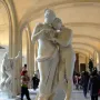 Standing Psyche and Love marble sculpture displayed on a pedestal in a museum gallery with visitors in the background.