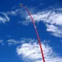 Wind Wand sculpture curving upward against a blue sky with scattered clouds.