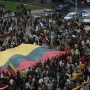 Large crowd holding a huge yellow green and red flag near the Bronze Soldier monument.