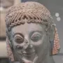 Marble head of the Rampin Rider with elaborate curls, a laurel wreath, and a damaged nose.