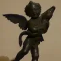 Bronze putto with a dolphin, the winged child poised on one foot atop a small base.