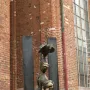 Bronze Bremer Stadtmusikanten sculpture with a donkey, dog, cat, and rooster stacked in a tower against a brick wall.