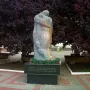 The Shot in the Back monument showing two figures embracing, one carrying the other on its back, on a dark base outdoors.