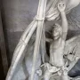 Angelo Nocchiero, a winged marble angel standing in a boat and holding ropes beside a mast and furled sails.