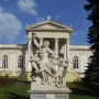 Laocoön sculpture of three figures entangled with serpents on a tall stone pedestal