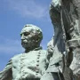 Close-up of the bronze General Philip Sheridan statue with a green patina against a blue sky.