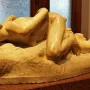 Malgré Tout sculpture of a reclining nude woman on a museum display stand