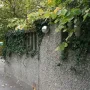 A polished spherical sculpture mounted on a textured concrete wall with ivy and a metal plaque below.