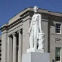 Abraham Lincoln statue on a stone pedestal in front of a classical courthouse building.
