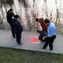 Five men stand beside the Keyboard Monument, looking at a large red panel with raised square blocks laid on a concrete path near the water.