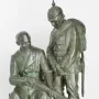 Dreyse Monument showing a seated man holding a rifle beside a standing soldier in a spiked helmet.