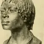 Bronze bust of Woman of Central Africa with short textured hair and layered beaded necklaces on a dark base.