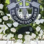 A memorial wreath with white and pale pink flowers, centered on a black Special Forces emblem and a black beret at America\'s Response Monument.