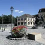 Anscavallo, a large abstract equine sculpture on a paved square with flower planters and streetlamps nearby.