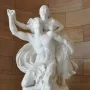 Mercury and Psyche sculpture showing a muscular male figure lifting a draped female figure against a curved stone wall.