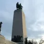 The This Is the Place Monument with three bronze men standing on a stone pedestal against a blue sky.