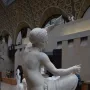 Jeune fille de Mégare, a white marble sculpture of a seated young woman holding a spindle and distaff