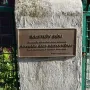 Bronze plaque for Kristek House mounted on a light-colored pillar beside a green metal fence.