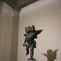 Bronze putto with a dolphin, the winged child poised on one foot atop a small base.