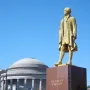 Alexander Hamilton statue on a stone pedestal with a domed classical building in the background