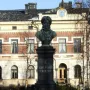 Frans Michael Franzén statue on a tall stone pedestal with a historic building and bare trees behind it.