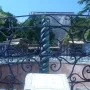 A section of the Serpent Column beside an ornate black wrought-iron fence, with a stone plaque block in the foreground.