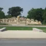Fountain of Time stone monument with a central robed figure and smaller sculpted figures arranged in a wave-like form.