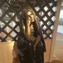 La Douleur, a dark metal sculpture of a draped figure with one hand to the cheek, standing on a plinth.