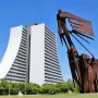 Monument to the Azoreans standing on a green lawn with a modern building in the background.