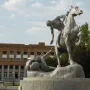 The Torch Bearers sculpture in front of a brick building under a cloudy sky.