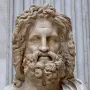 Marble bust of Zeus of Otricoli with a bearded face and curly hair, displayed on a pedestal in a museum gallery.