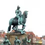 Christian V equestrian statue showing an armored rider on a rearing horse atop an ornate pedestal with sculptural figures.