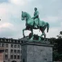 Albert I equestrian statue on a stone pedestal in a public square, with buildings and steps in the background.