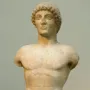 Apollo Strangford marble kouros statue with missing arms and lower legs, shown frontally on a dark base.