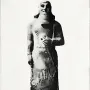 Statue of Ashurnasirpal II standing on a rectangular base, with a long carved garment and prominent beard.