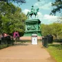Major General John A. Logan equestrian statue on an ornate pedestal in a park, with a notice sign nearby.