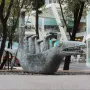 How Doth the Little Crocodile sculpture with a metallic reptile head and smaller figures inside.