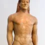 The Kroisos Kouros, a nude male marble statue standing with arms at its sides and braided hair.