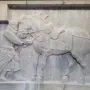 Limestone relief from the Six Steeds of Zhao Mausoleum showing a uniformed figure beside a saddled horse.
