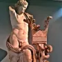 Apollo of Cyrene marble statue leaning on a carved column with a coiled snake, missing its right arm