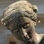 Close-up of The Cleveland Apollo’s bronze head with a greenish-brown patina and downward gaze.