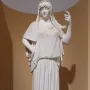 Giustiniani Hestia, a white marble statue of a standing woman in a long pleated robe with a mantle over her head and shoulders.